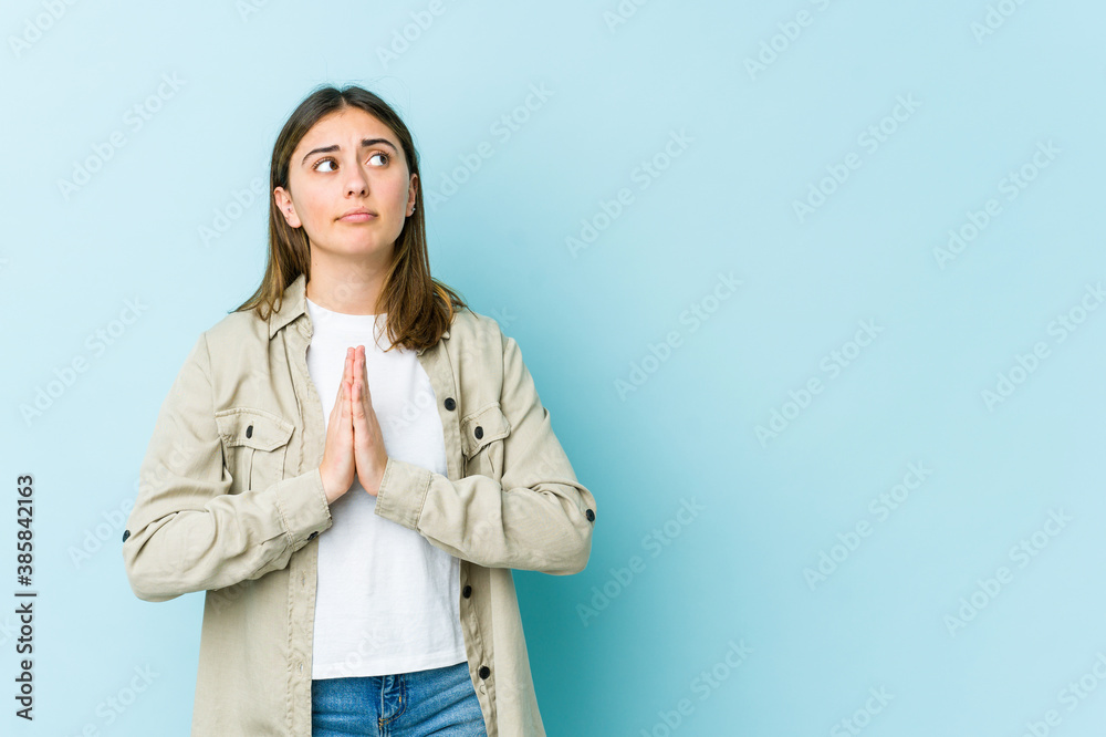 Young caucasian woman holding hands in pray near mouth, feels confident. Young caucasian woman holding hands in pray near mouth, feels confident.