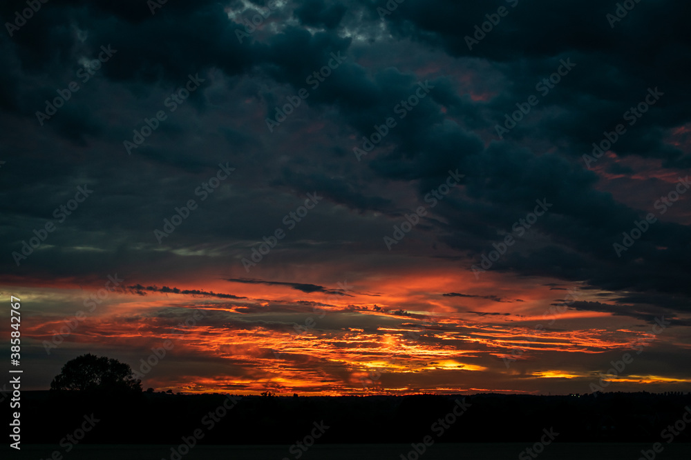Fototapeta premium Beautiful wide angle view for dramatic sunset sky with clouds, astonishing sun set in bright colors on British agricultural grounds, most amazing view in UK, high contrast and saturation photography