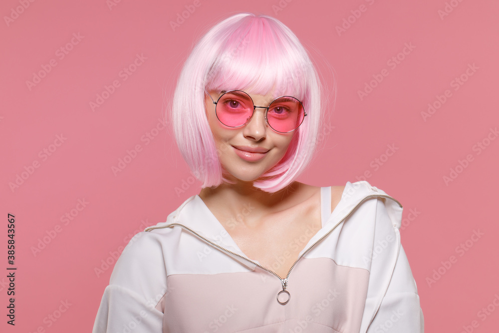 Close-up portrait of young smiling funky woman with pink hair wearing sweatshirt and eyeglasses, enjoying party and her fancy look