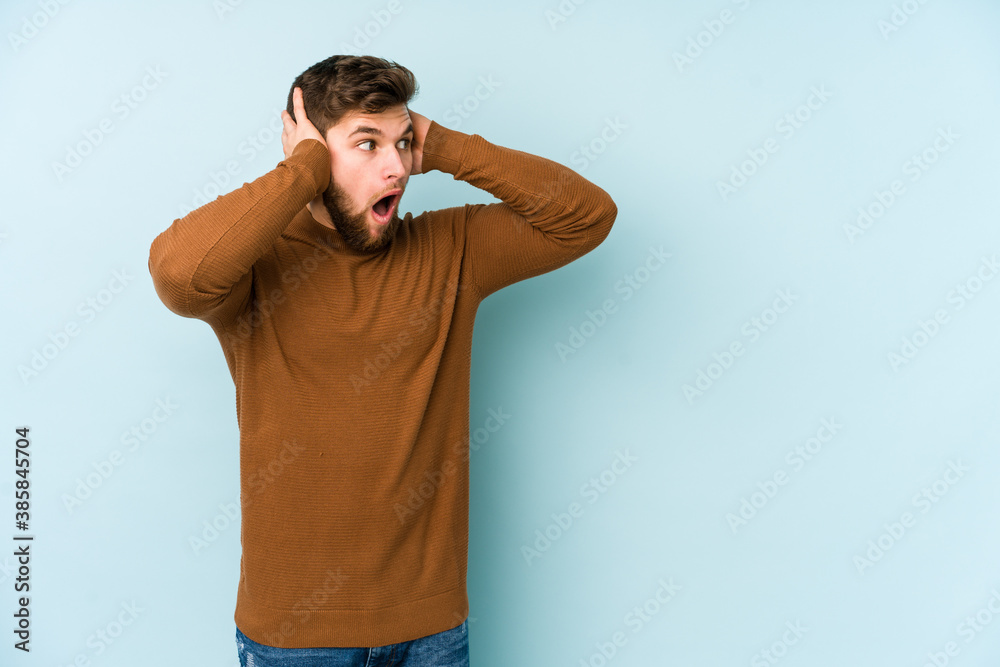 Young caucasian man isolated on blue background screaming, very excited, passionate, satisfied with something. Young caucasian man isolated on blue background screaming, very excited, passionate, satisfied with something.