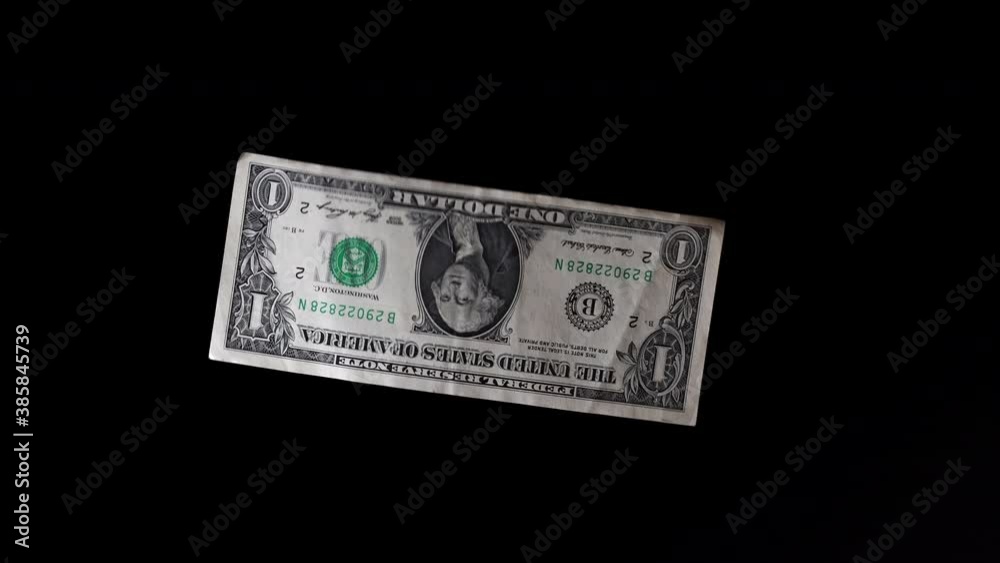A one dollar banknote fluttering on a black background. A dollar bill flies in the wind. A one dollar banknote fluttering on a black background. A dollar bill flies in the wind.