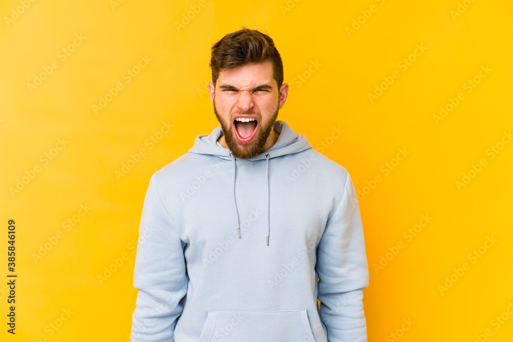 Young caucasian man isolated on yellow background shouting very angry, rage concept, frustrated. Young caucasian man isolated on yellow background shouting very angry, rage concept, frustrated.