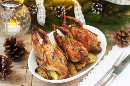 Baked quail with potatoes and onions on a festive background. Rustic style.