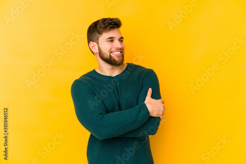 Young caucasian man isolated on yellow background smiling confident with crossed arms.