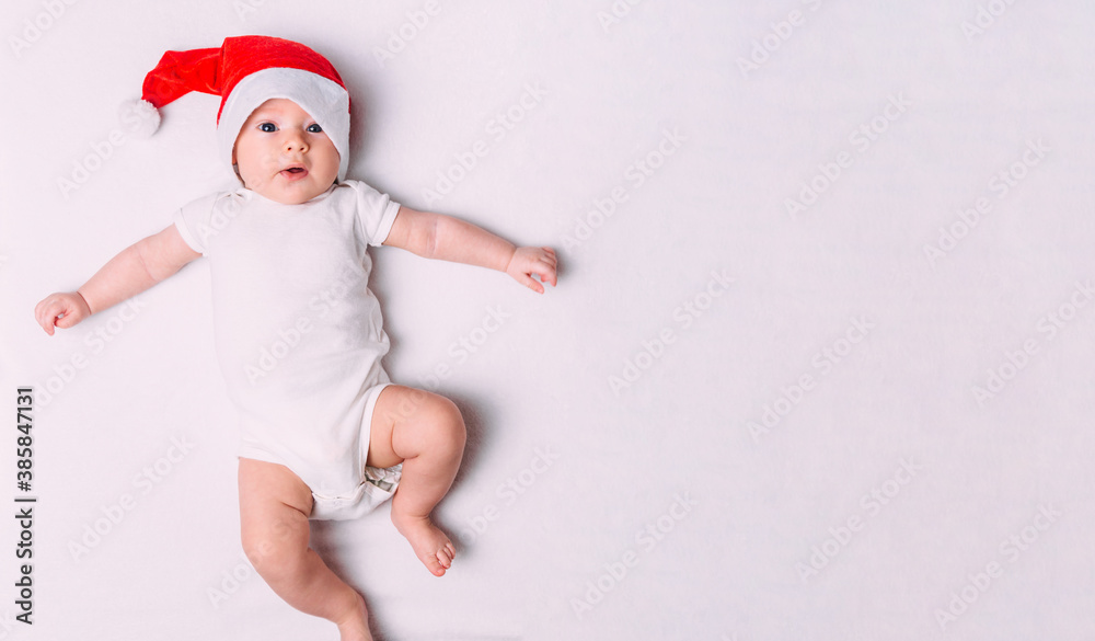 Cute little baby in Santa hat on soft fabric. Baby first christmas. Santa baby. New Year's holidays. Cute little baby in Santa hat on soft fabric. Baby first christmas. Santa baby. New Year's holidays.