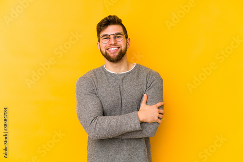 Young caucasian man isolated on yellow background laughing and having fun.