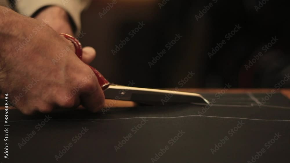 hand cutting with scissors a piece of black cloth on the chalk hand cutting with scissors a piece of black cloth on the chalk