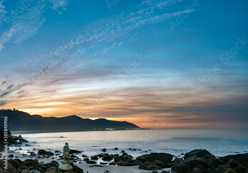 Delicately balanced rocks stacked on the shoreline of Mussel Shoals is backlit by morning sunrise. photo