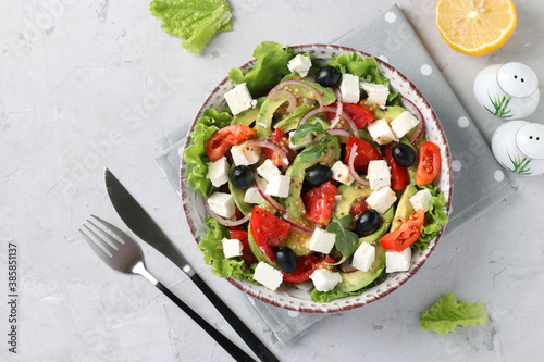 Healthy salad with avocado, tomatoes, feta, black olives and red onion on grey background, healthy eating day, Top view