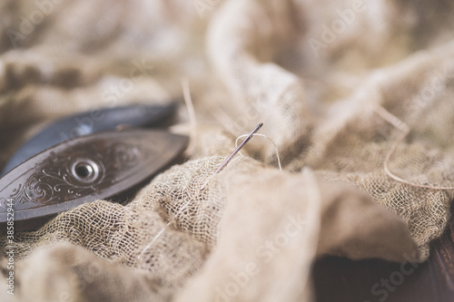 Closeup of Needle and Thread on Beige Fabric with Antique Tatting Shuttles in Background