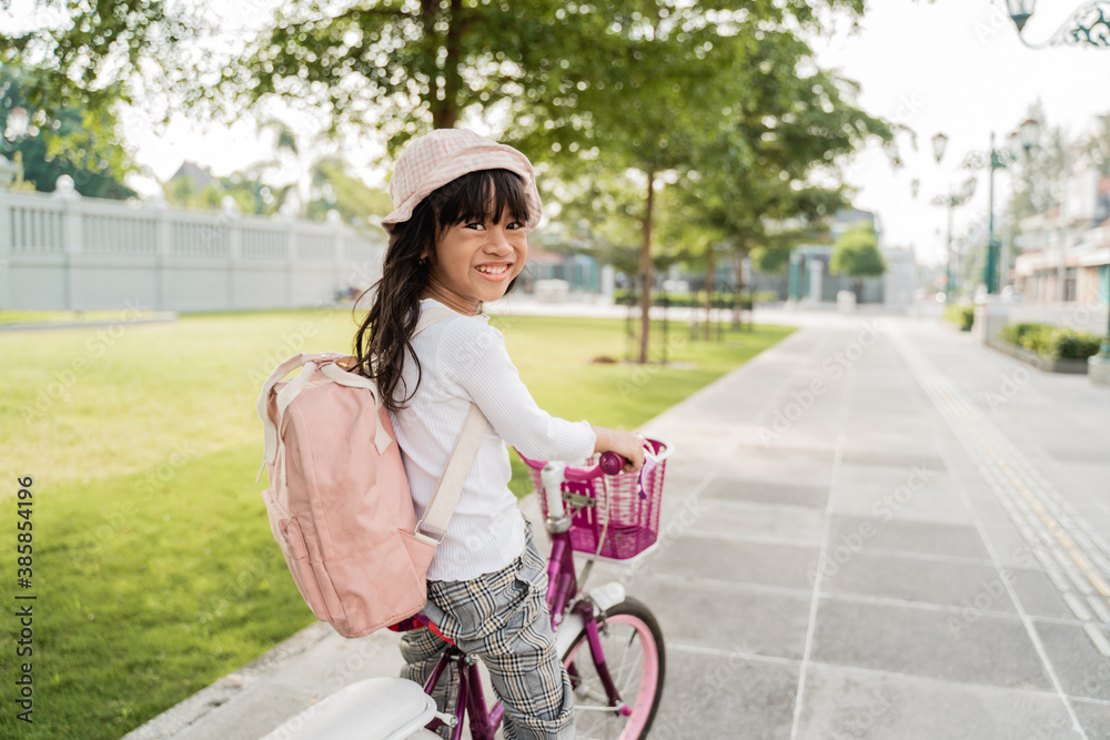 Φωτογραφία a portrait of a cheerful and happy little girl riding a bicycle in the park goin