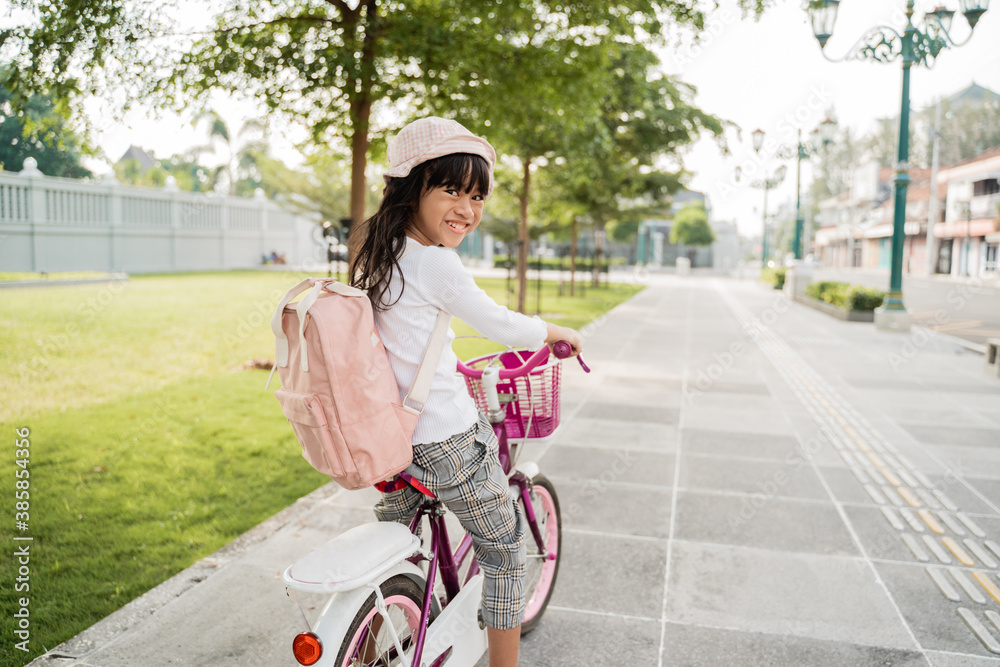 Φωτογραφία a portrait of a cheerful and happy little girl riding a bicycle in the park goin