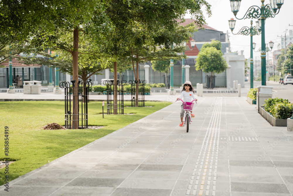 Φωτογραφία a portrait of a cheerful and happy little girl playing a bicycle in the park whe