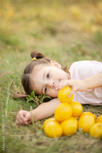 Cute little girl in nature with lemon under lemon tree in summer