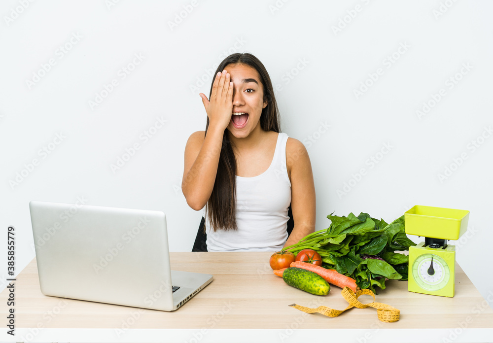 Young dietician asian woman isolated on white background having fun covering half of face with palm. Young dietician asian woman isolated on white background having fun covering half of face with palm.