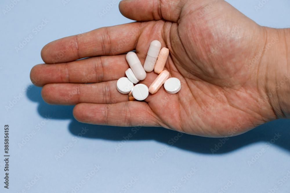 A lot of pills on human hand isolated. Caucasian man is holding a lot of different pills in his hand. A lot of pills on human hand isolated. Caucasian man is holding a lot of different pills in his hand.