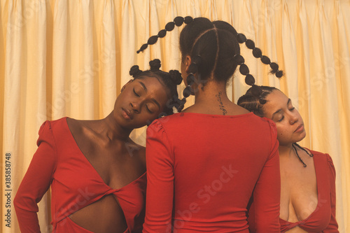 Two Black models with eyes closed heads resting on shoulder of third model photo