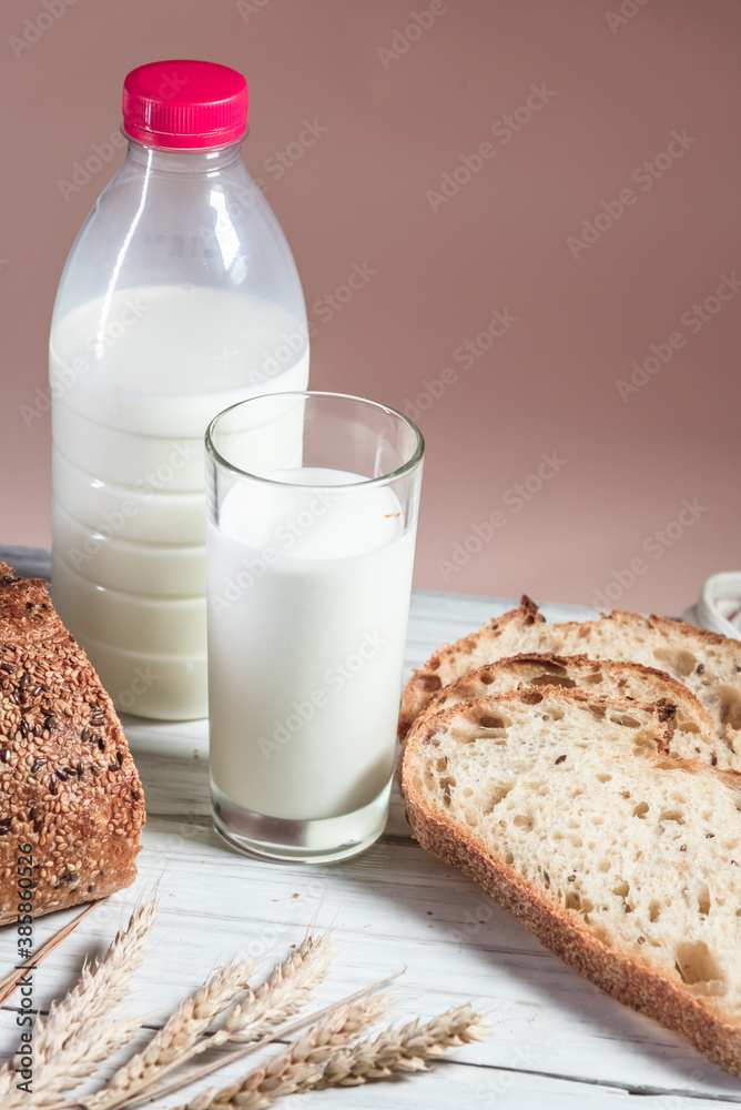 A glass of milk, sliced rustic bread and jam, on a white wooden board. Healthy food and farming concept A glass of milk, sliced rustic bread and jam, on a white wooden board. Healthy food and farming concept