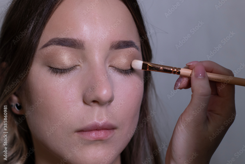 Obraz premium the process of applying makeup to a beautiful brunette. beauty, modeling and cosmetics concept. 