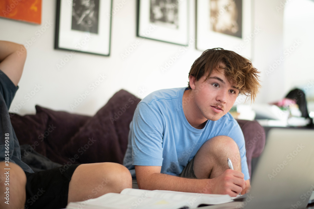 teen boy doing homework in house setting Stock Photo | Adobe Stock