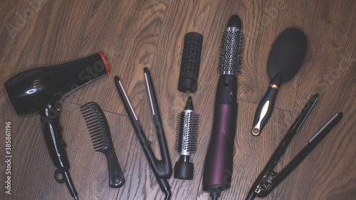 Hairdressing tools on a wooden background. Combs and hair dryer, hair straightener. Long hair curls. Extension hair care.