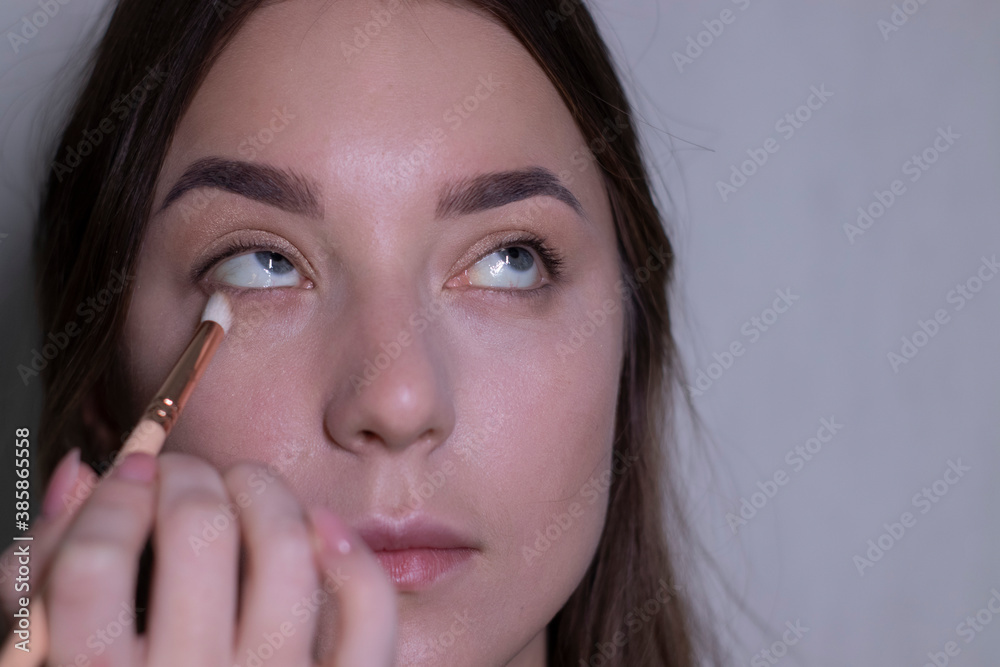 the process of applying makeup to a beautiful brunette. beauty, modeling and cosmetics concept. the process of applying makeup to a beautiful brunette. beauty, modeling and cosmetics concept.