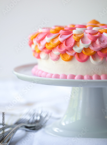 Tri-colored Orange Pink White Frosted Layer Cake on White Pedestal Cake Stand