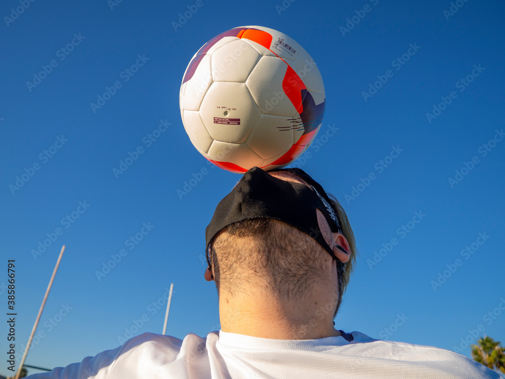 Hombre gordo jugando al futbol en un campo de futbol con mascarilla