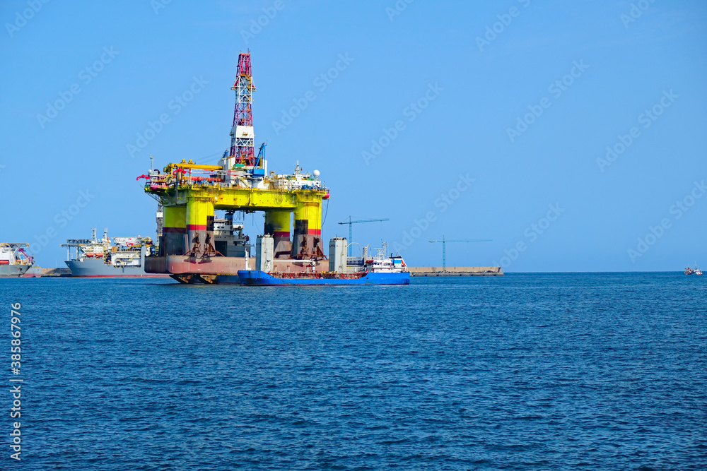 Huge crude oil rig equipment and a service ship on the water.