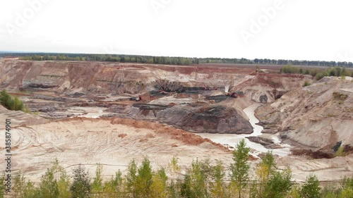 Clay or iron ore mining quarry. Machinery trucks in lithium mine. Large construction site with heavy equipment. Heavy duty trucks. Industrial site. Mining industry. Extraction of minerals