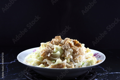 Fried and stirred rice noodle with dried tofu, cutting Chinese cabbage and cauliflower on the plate. Famous vegetarian menu in Asia restaurant. High fiber and low fat menu.