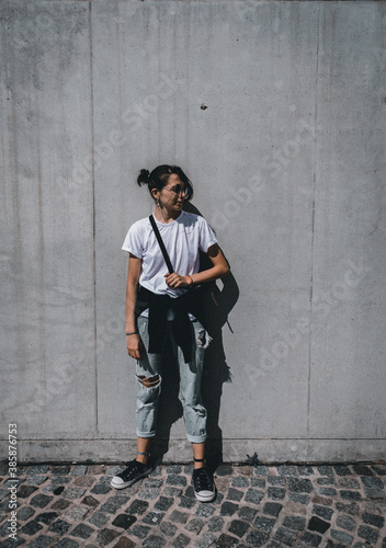 young woman looking straight ahead, brick background, feminine concept, urban fashion