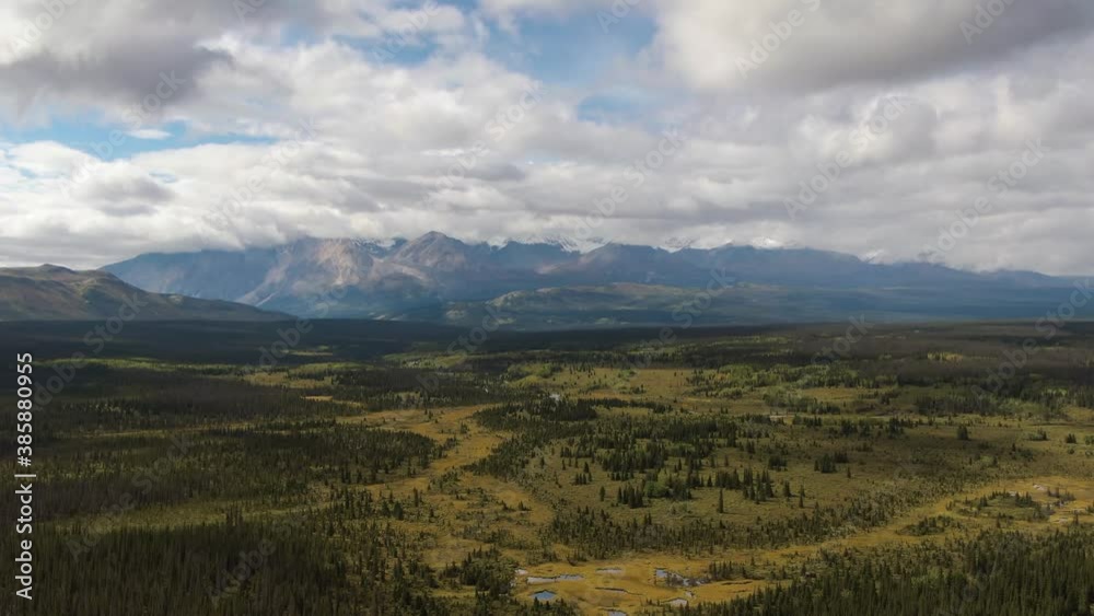 Beautiful View of Lush Forests, Trees and Land surrounded by Mountains on a Cloudy Summer Day in Canadian Nature. Aerial Drone Shot. Taken near Alaska Highway, Yukon, Canada. Beautiful View of Lush Forests, Trees and Land surrounded by Mountains on a Cloudy Summer Day in Canadian Nature. Aerial Drone Shot. Taken near Alaska Highway, Yukon, Canada.
