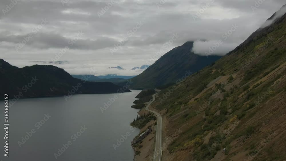 Beautiful View of Scenic Road alongside Peaceful Lake surrounded by Mountains in Canadian Nature. Aerial Drone Shot. Taken by Klondike Highway, South of Carcross, Yukon, Canada. 4K Beautiful View of Scenic Road alongside Peaceful Lake surrounded by Mountains in Canadian Nature. Aerial Drone Shot. Taken by Klondike Highway, South of Carcross, Yukon, Canada. 4K