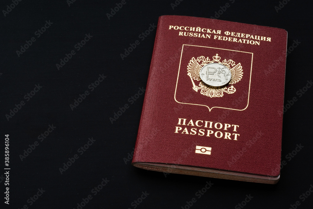 Russian foreign passport with ruble coin on black background. Copy space