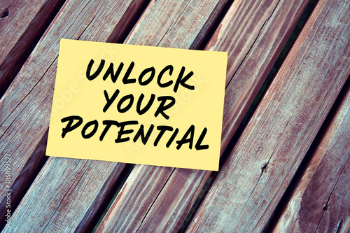 Unlock your potential. Motivational or inspirational quote handwritten on paper on a wooden table.