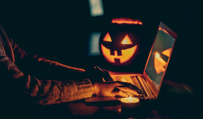 Halloween evening at the computer. Woman talking on the feast of Halloween on the internet. Coronavirus pandemic time concept. Shallow depth of field and noise.