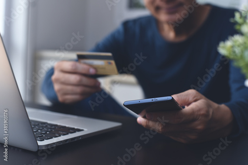 Man using credit card for online shopping and internet payment or digital banking on mobile smart phone at home