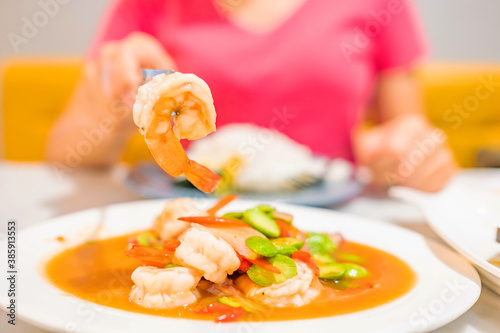 Woman is eating Stir Fried Sator beans with Shrimp on white plate.Thai food.  Copy space. photo