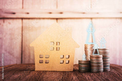 Wood home model on table with finacial coin and business graph in vintage tone