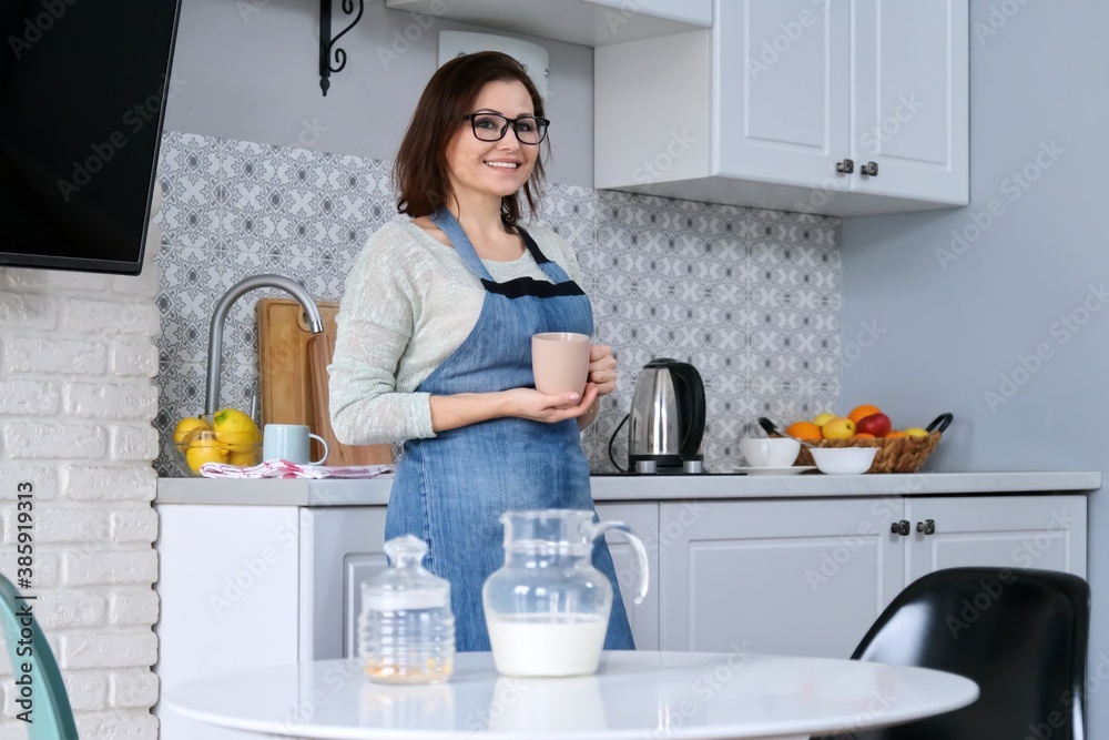 Portrait of mature woman housewife in an apron at home in the kitchen Portrait of mature woman housewife in an apron at home in the kitchen