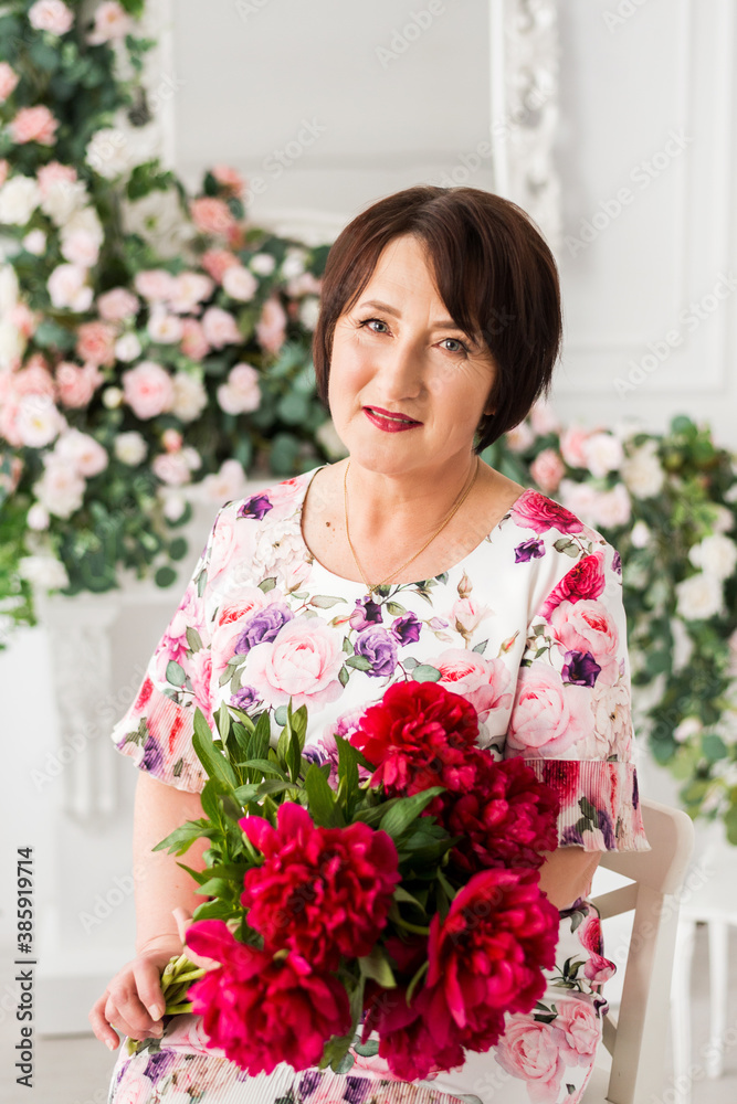 Beautiful senior woman at home with a bouquet of flowers. Happy Mother's Day. Beauty, fashion. Happy retirement.