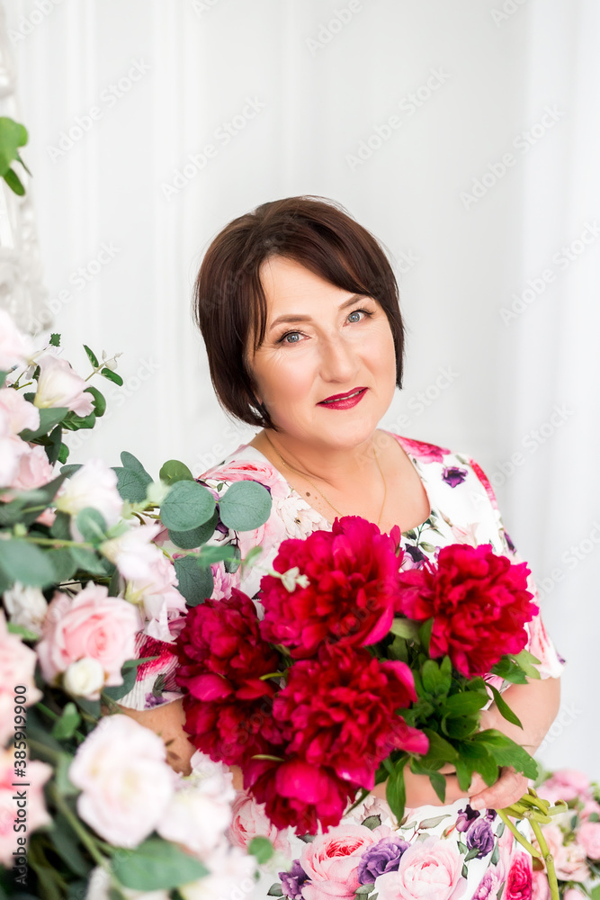 Beautiful senior woman at home with a bouquet of flowers. Happy Mother's Day. Beauty, fashion. Happy retirement.