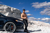 Close up portrait of a young shirtless man standing near his car outside. White quarry background.