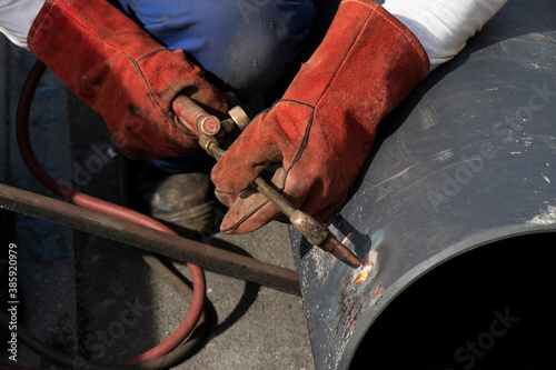 Welder worker welding a wide metal pipe tube with a oxy-fuel cutting torch