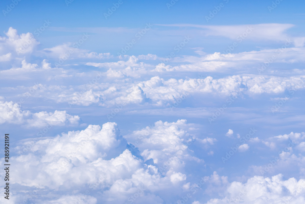 Aerial view of cloudscape seen through airplane window. Bright blue sky and white clouds. Skyline background with copy space. Aerial view of cloudscape seen through airplane window. Bright blue sky and white clouds. Skyline background with copy space.