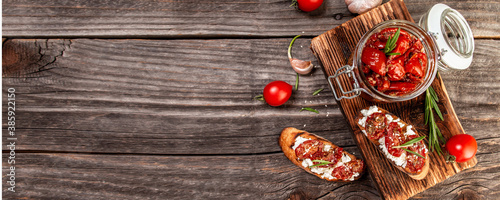 sandwich with goat cheese, sun-dried tomatoes and garlic, oregano, olive oil wooden textured background. space for text. top view. Long banner format