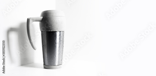 Thermo mug sprayed with water on white, isolated background with copy space.