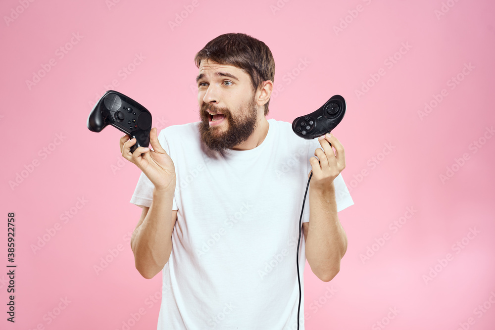 Man with two joysticks in hands fun game technology lifestyle pink background Man with two joysticks in hands fun game technology lifestyle pink background