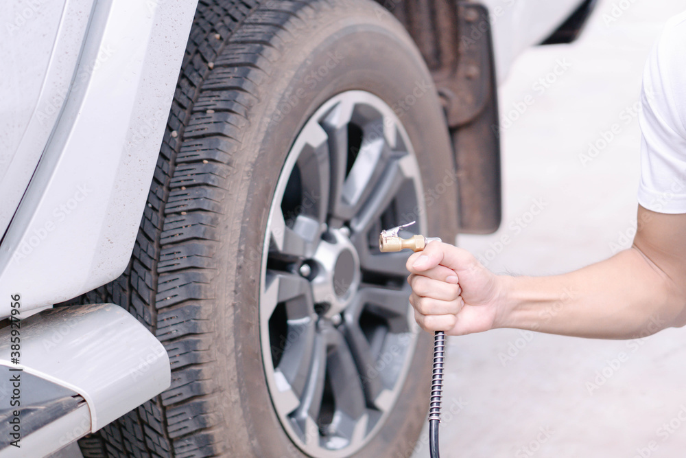 Close up man hand holding mechanic inflating tire and checking air pressure with gauge pressure in service station Close up man hand holding mechanic inflating tire and checking air pressure with gauge pressure in service station